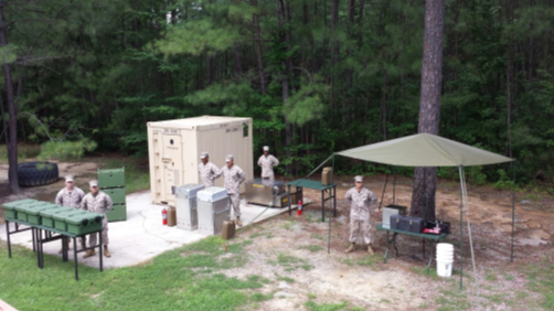 Several Marines stand near the Enhanced Tray Ration Heating System